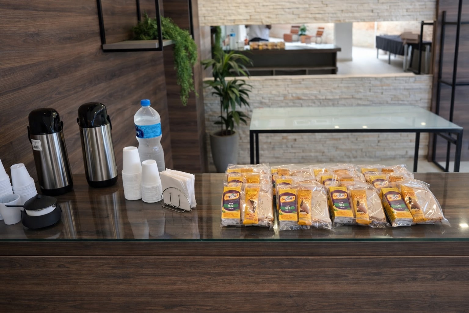 Café no Trabalho. 1 café no trabalho em cima de uma bancada com kit lanches e garrafas de café e água.