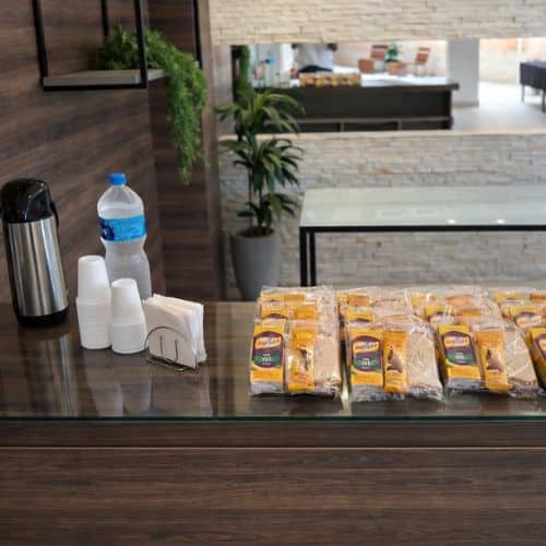 Coffee break simples com kits individuais organizados em ambiente corporativo para reuniões e treinamentos.
